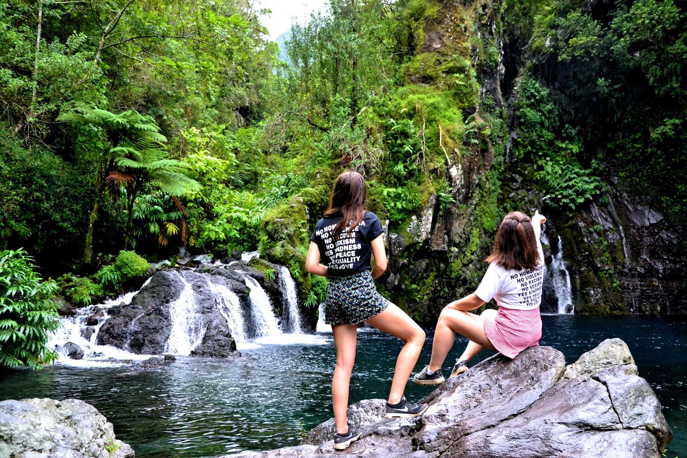 Two women enjoying a breathtaking view of a waterfall surrounded by lush greenery.
